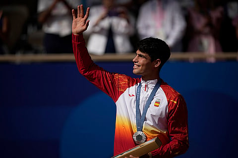Carlos Alcaraz waves while wearing his silver medal after losing to Novak Djokovic